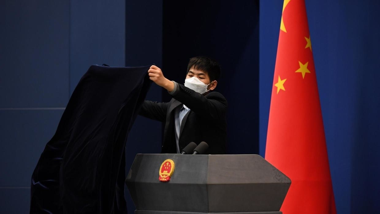 A worker covers the podium after a Chinese Foreign Ministry media briefing in Beijing on March 18, 2020. AFP - GREG BAKER