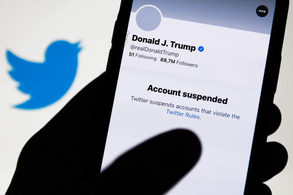 Donald Trump's Twitter account displayed on a phone screen and Twitter logo in the background are seen in this illustration photo taken in Poland on January 9, 2021. Twitter suspended Donald Trump's account because of violating the app rules. &#