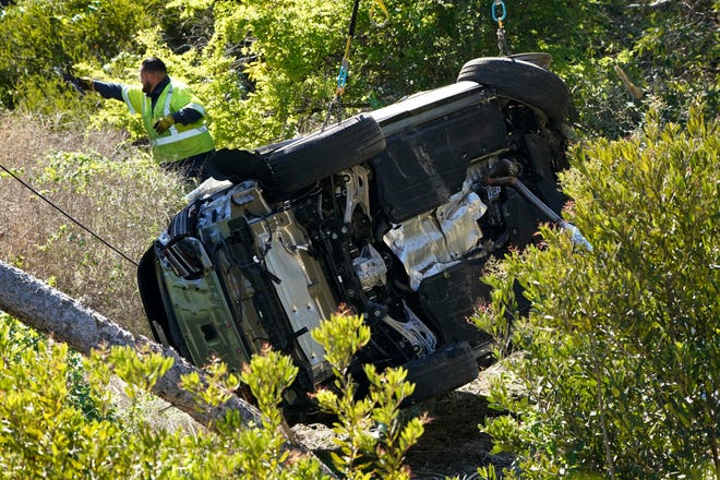 Workers move a vehicle on its side after a rollover accident involving golfer Tiger Woods on Feb. 23, 2021, in the Rancho Palos Verdes section of Los Angeles.  Marcio Jose Sanchez, AP