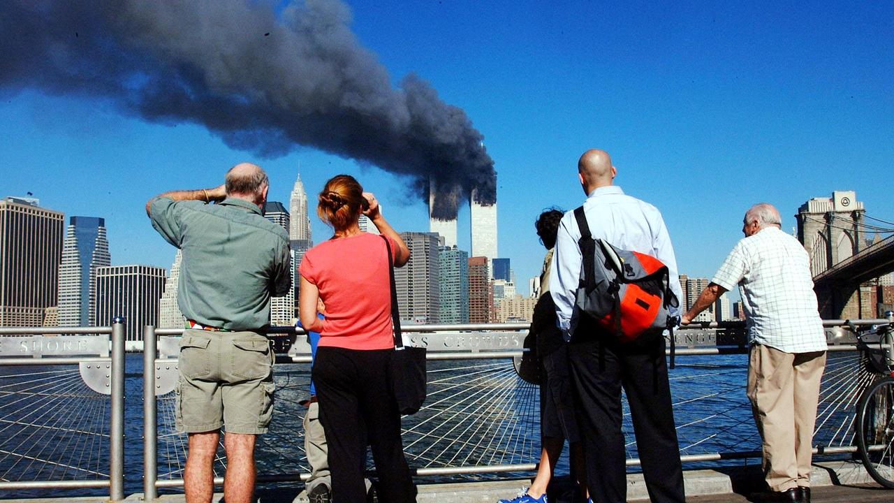 Pedestrians standing on the Brooklyn waterfront look across the East River towards the burning twin towers of the World Trade Center. Picture: HENNY RAY ABRAMS / AFP