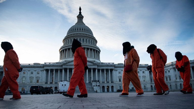 Demonstrators dressed in Guantanamo Bay prisoner uniforms march past Capitol Hill in Washington, DC. ©  AFP / Brendan Smialowski
