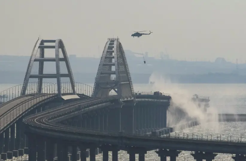 A helicopter drops water to extinguish fuel tanks ablaze on the Kerch bridge in the Kerch Strait, Crimea (photo credit: REUTERS)