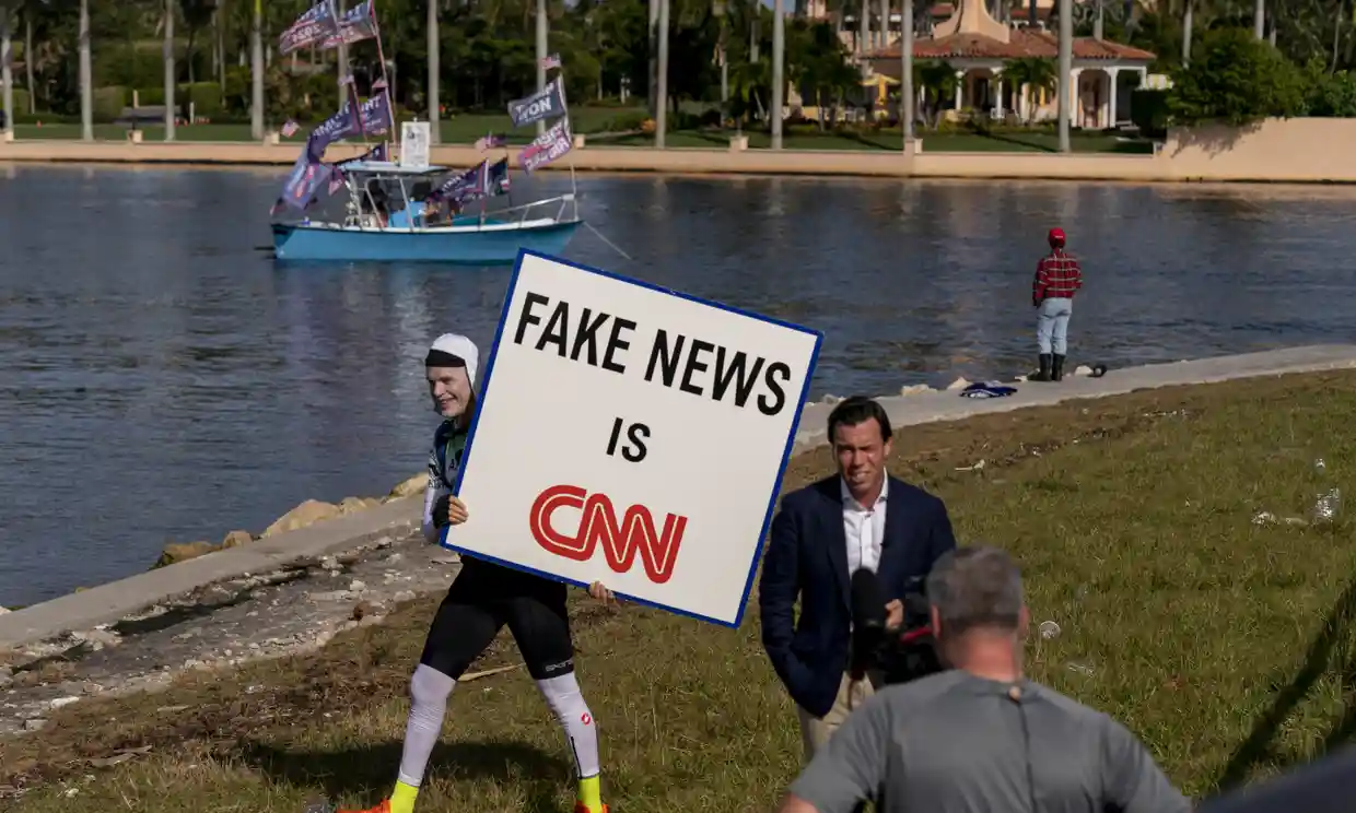 A man walks behind an on-air reporter outside Mar-a-lago, shortly before the former president announced his 2024 run. Photograph: Andrew Harnik/AP