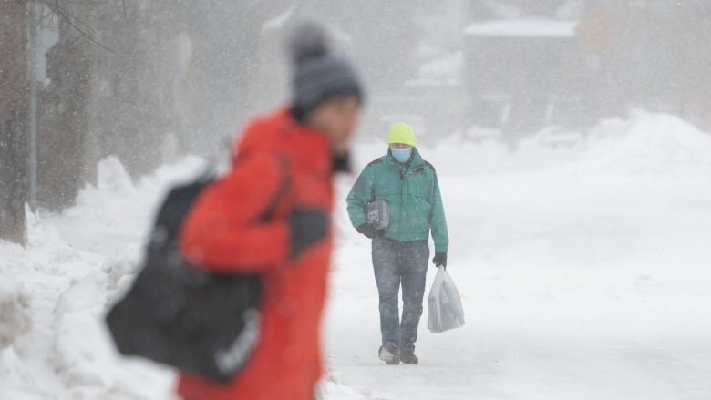 People make their way through the snow in Ottawa's Glebe neighbourhood on Saturday. (Spencer Colby/The Canadian Press)