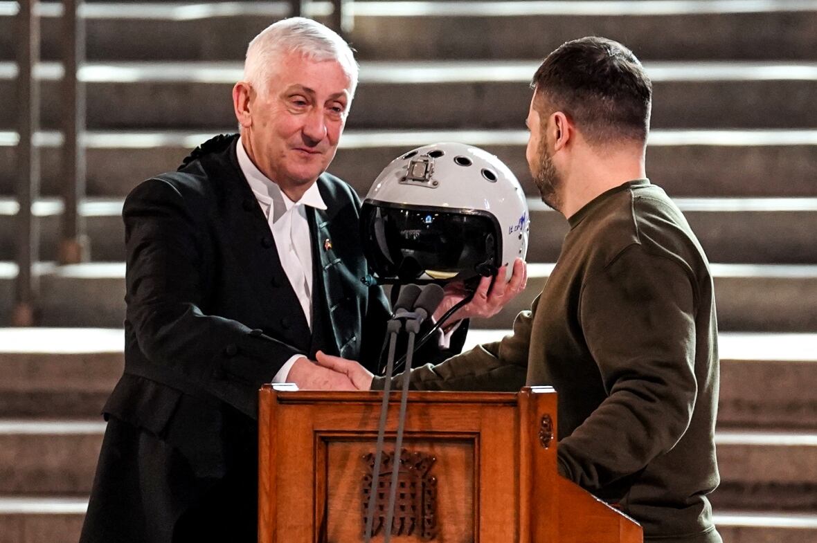 Sir Lindsay Hoyle, left, House of Commons Speaker, holds the helmet of a Ukrainian pilot presented to him by Zelenskyy on Wednesday at Westminster Hall in central London. (Stefan Rousseau/AFP/Getty Images)