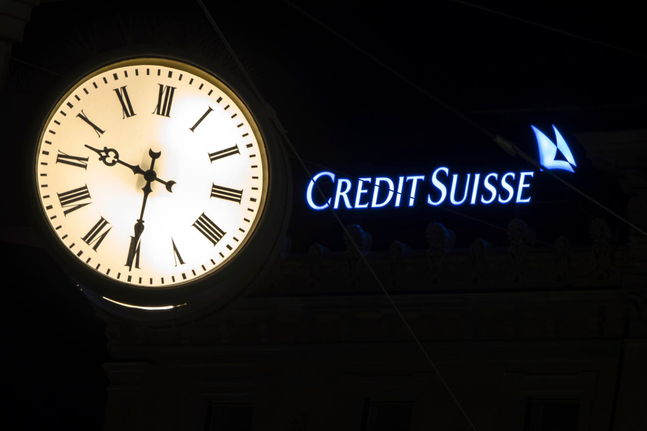 The illuminated logo of Swiss bank Credit Suisse is seen behind a clock at the banks headquarters at Paradeplatz in Zurich, Switzerland on Saturday, March 18, 2023. (Michael Buholzer/Keystone via AP)