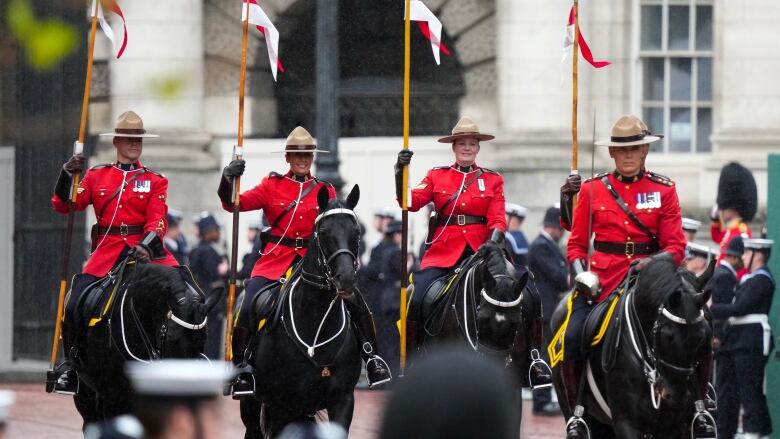 RCMP officers ride in front of King Charles and Queen Camilla’s carriage during the royal procession following the coronation ceremony in London on Saturday. (Nathan Denette/The Canadian Press)