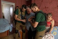 Volunteers prepare to evacuate a man named Oleksandr, largely immobile after a stroke, and his wife, Natalya, from their fourth-floor apartment in Kupyansk, Ukraine. (Heidi Levine for The Washington Post)