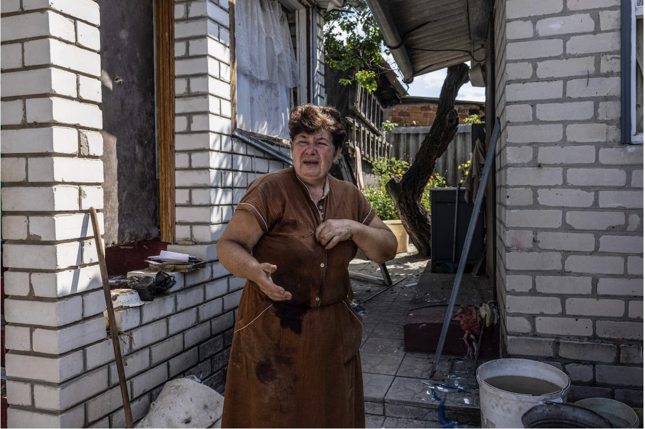 Tokareva's childhood friend Tetiana Skrynnikova, her dress stained by blood from her own injuries, cries outside her home after Tokareva's death. (Heidi Levine for The Washington Post)