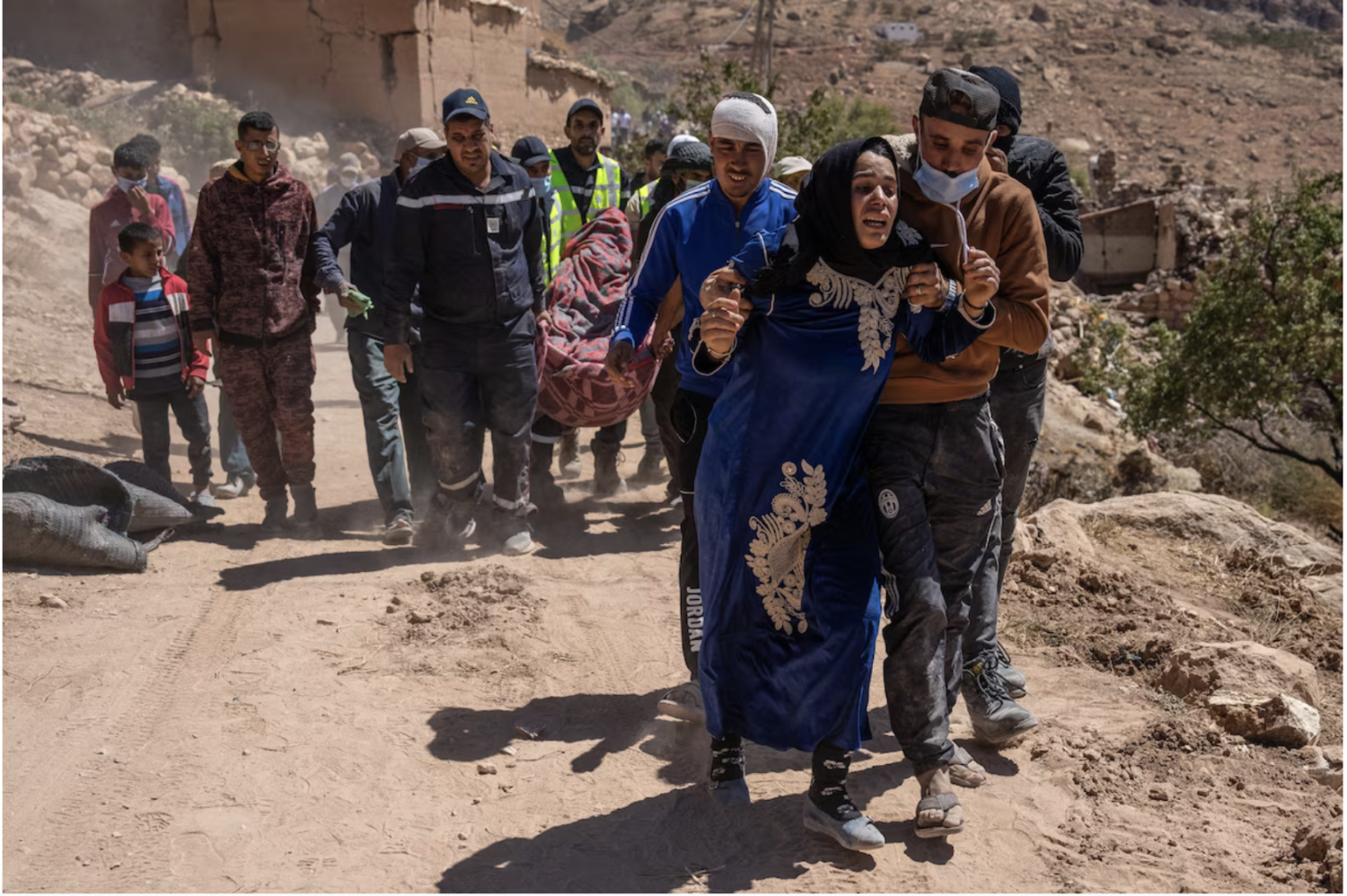 A woman is overcome with grief as her husband's body is carried for burial after being removed from beneath a collapsed house in Douzrou, Morocco, on Monday. (Carl Court/Getty Images)