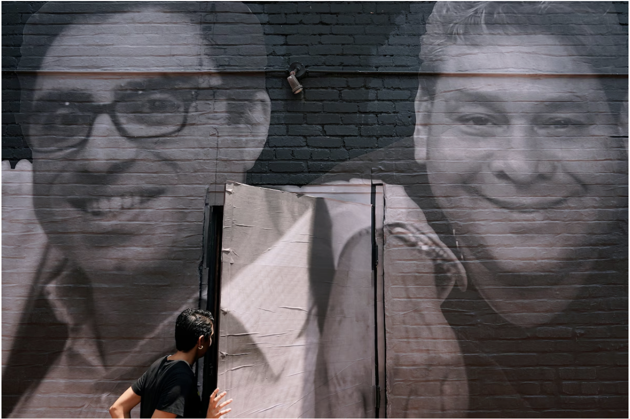 A woman steps through a door at a building in Washington decorated with a mural depicting American hostages and wrongful detainees held abroad. At left is Siamak Namazi, who has been in captivity in Iran since 2015. At right is Jose Angel Pereira, who had been imprisoned in Venezuela before his release last year. (Patrick Semansky/AP)