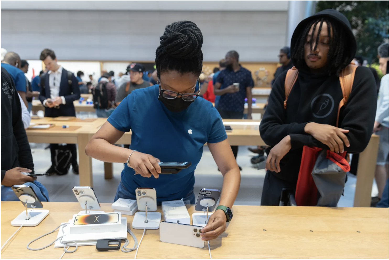 An Apple Store employee helps a customer with an iPhone purchase. Jeenah Moon/Bloomberg via Getty Images