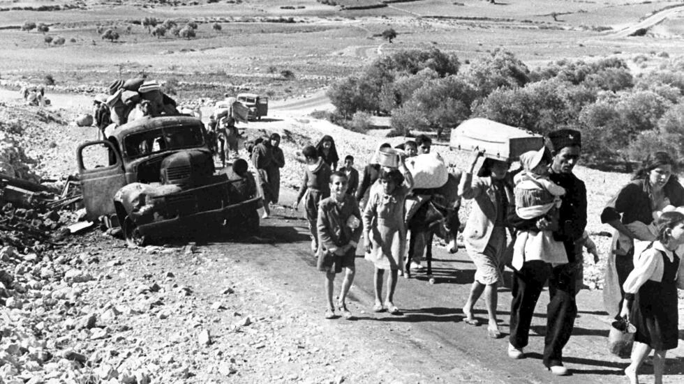 A group of Arab refugees carrying their belongings walks along a road from Jerusalem to Lebanon on November 9, 1948. © Jim Pringle, AP