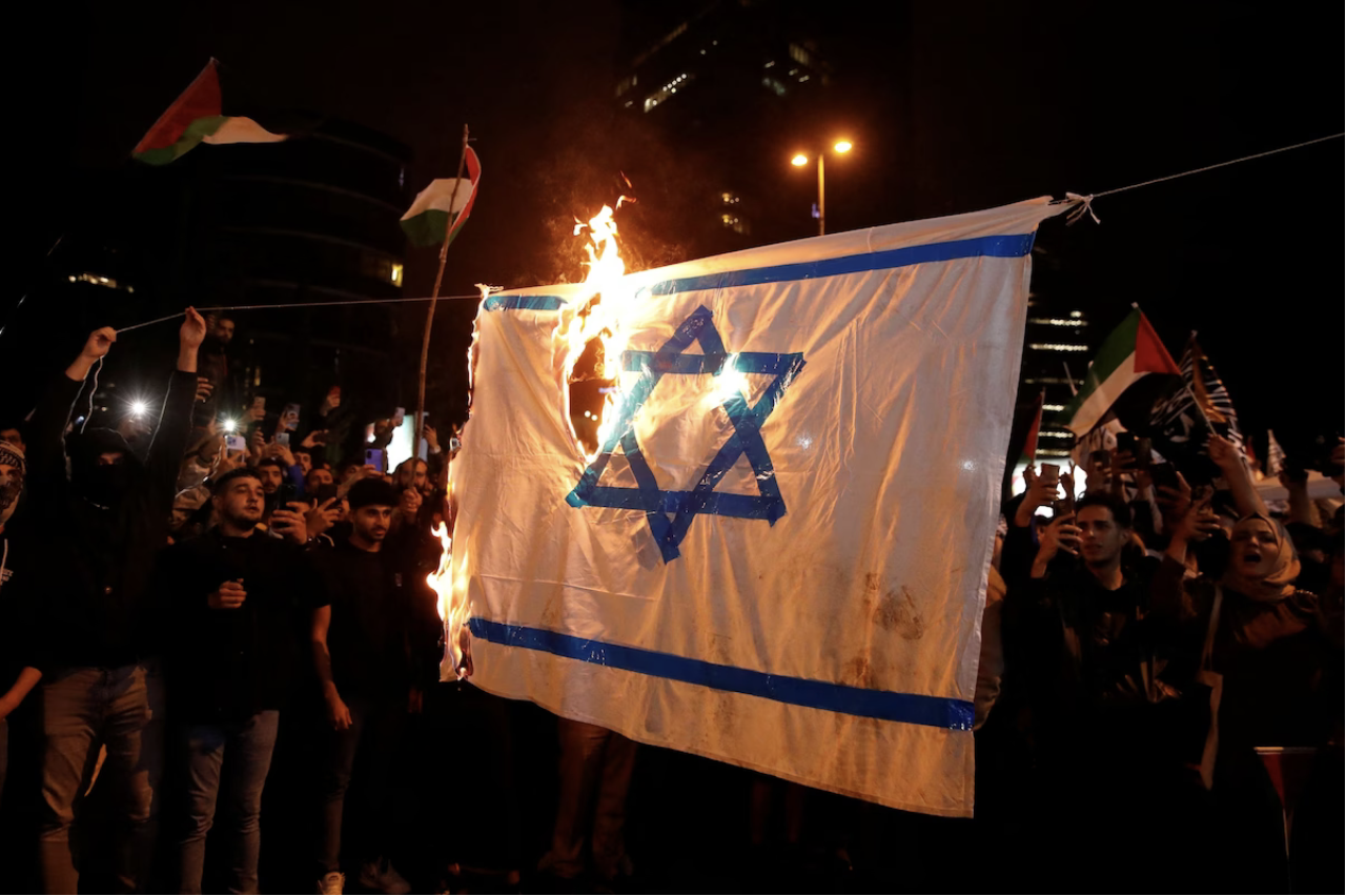 Demonstrators set fire to a makeshift Israeli flag near the Israeli Consulate in Istanbul on Wednesday. (Dilara Senkaya/Reuters)
