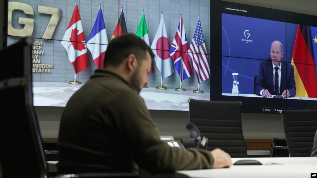 Ukrainian President Volodymyr Zelenskyy, left, and German Chancellor Olaf Scholz, right on the screen, attend the video conference of the leaders of the Group of Seven and Ukraine, in Kyiv, Ukraine, Oct. 11, 2022.