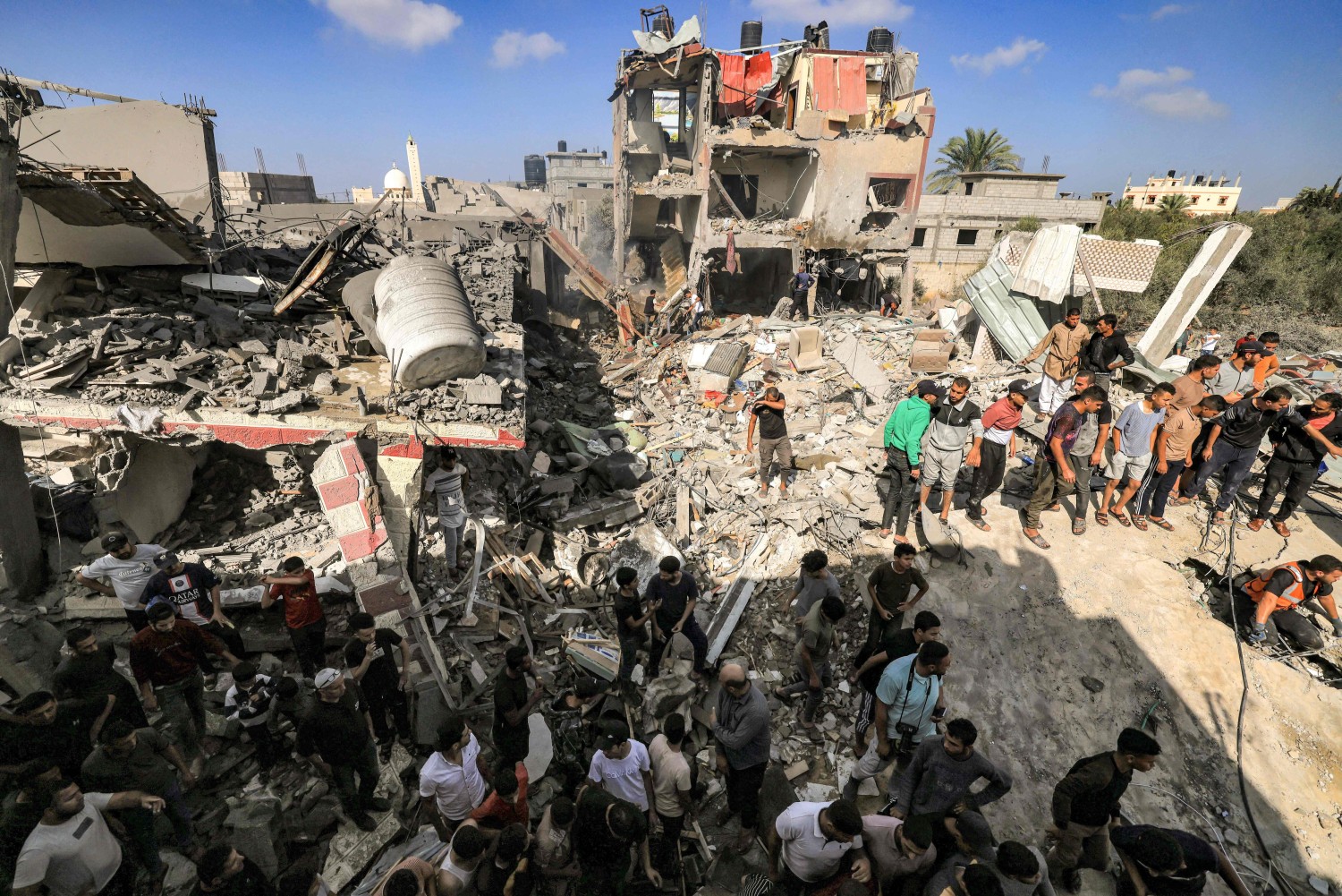People gather by a collapsed building after an Israeli strike in Khan Yunis in the southern Gaza Strip. MAHMUD HAMS/AFP/GETTY IMAGES