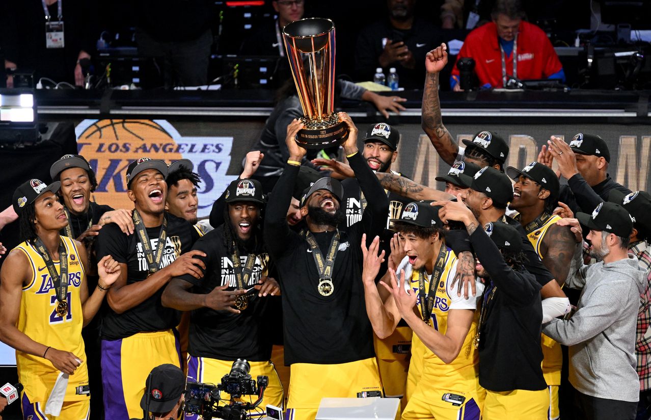 LeBron James hoists the NBA Cup and celebrates with Lakers teammates. CANDICE WARD/REUTERS