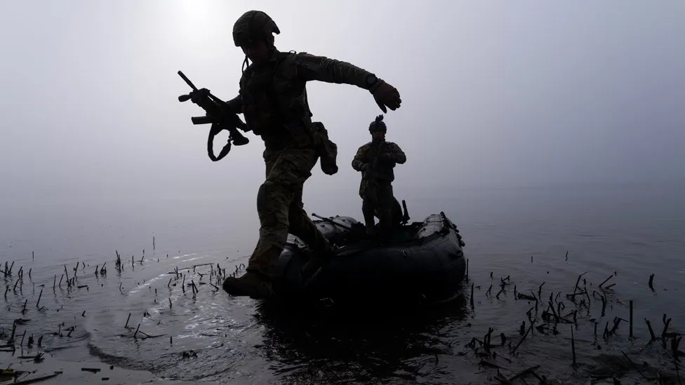 A Ukrainian serviceman jumps out of a boat on the shore of the Dnipro river. AP