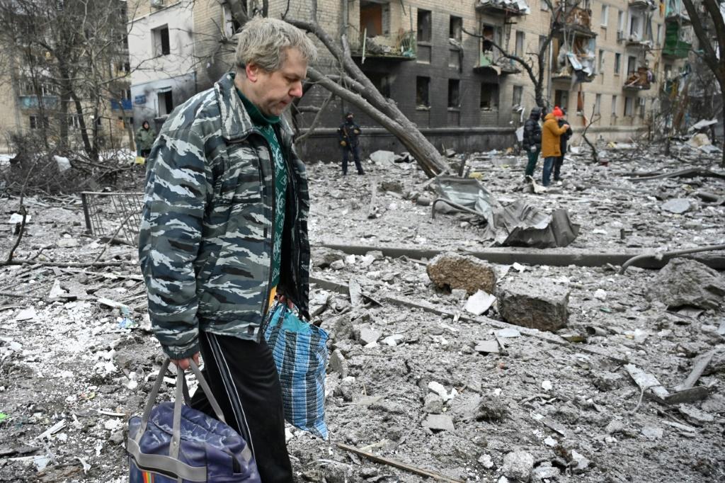 A Kharkiv local walks across debris near a residential building damaged in a missile attack