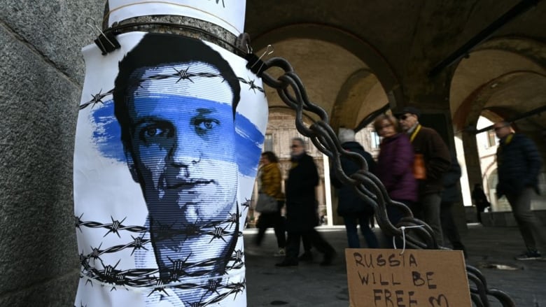 People walk past a poster of the late Russian opposition leader Alexei Navalny in Milan, Italy, on Saturday. Navalny died in a Russian Arctic prison on Feb. 16. (Gabriel Bouys/AFP/Getty Images)