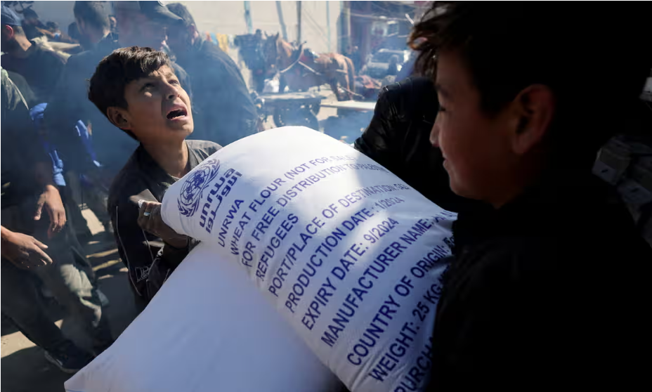 A Palestinian boy is given a bag of flour distributed by UNRWA in Rafah, southern Gaza. Many countries have paused funding after Israel’s allegations about UN staff. Photograph: Ibraheem Abu Mustafa/Reuters
