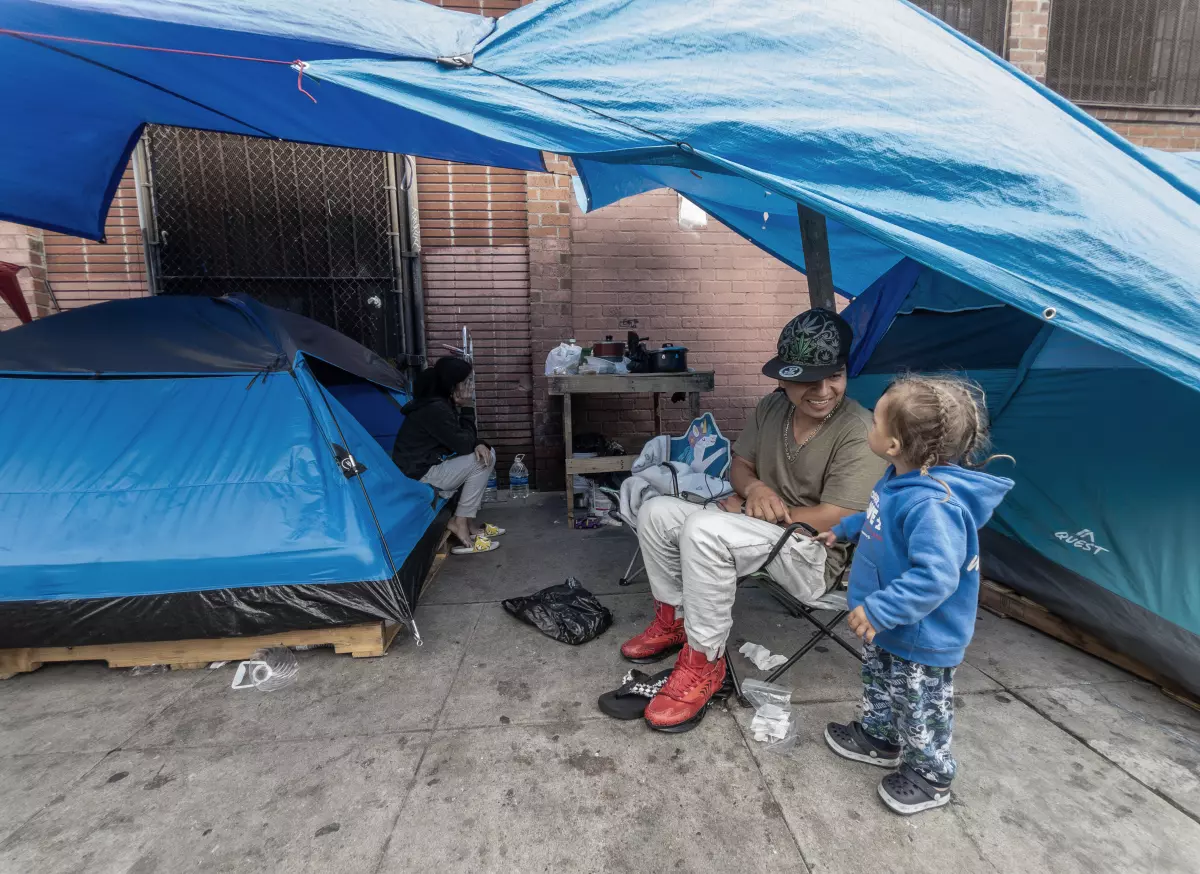 Jhon Valencia plays with Thian, 2, with his mother, Katherine Gonzalez, in the back, on Towne Avenue on Los Angeles’ Skid Row. (Myung J. Chun / Los Angeles Times)
