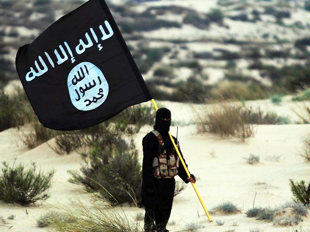 A masked Islamic State soldier poses holding the group’s banner. Picture: Getty Images