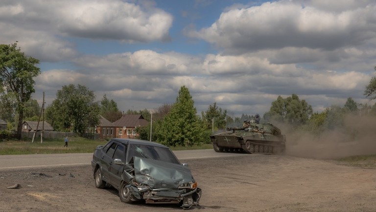A Ukrainian self-propelled howitzer drives past a damaged car on a road near Volchansk, Ukraine, May 12, 2024 ©  AFP / Roman Pilipey