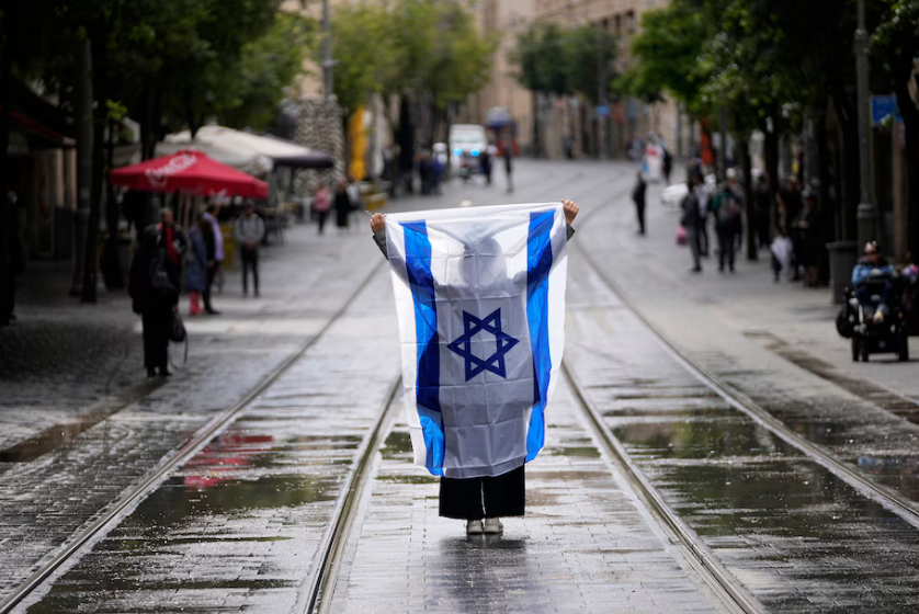 A woman stands with an Israeli flag during a two-minute siren in memory of victims of the Holocaust, in Jerusalem, May 6. (Ohad Zwigenberg/AP)