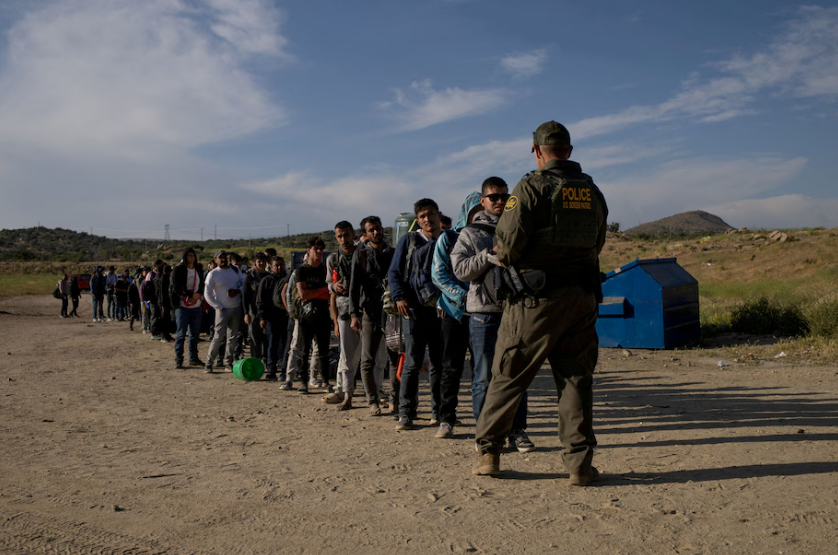 Migrants from Jordan, China, Egypt and Colombia surrender to a border patrol agent after crossing into the U.S. from Mexico in Jacumba Hot Springs, Calif., May 15, 2024. (Adrees Latif/Reuters)