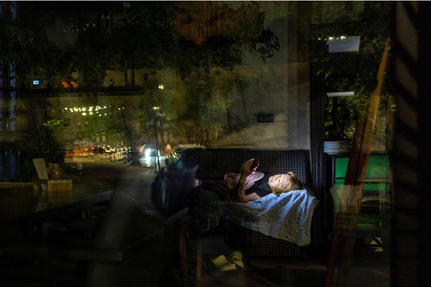 A woman lies down in a restaurant during a partial electricity cutoff in Kyiv last month. (Thomas Peter/Reuters)