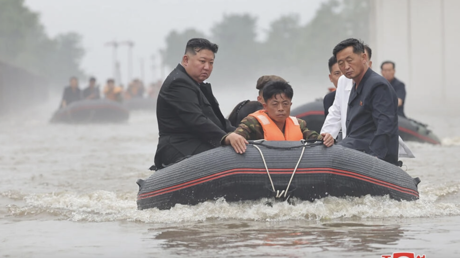 An undated photo released by North Korea's official Korean Central News Agency shows leader Kim Jong Un (left) in a dinghy as he inspects a floot-hit part of Sinuiju © STR / KCNA VIA KNS/AFP