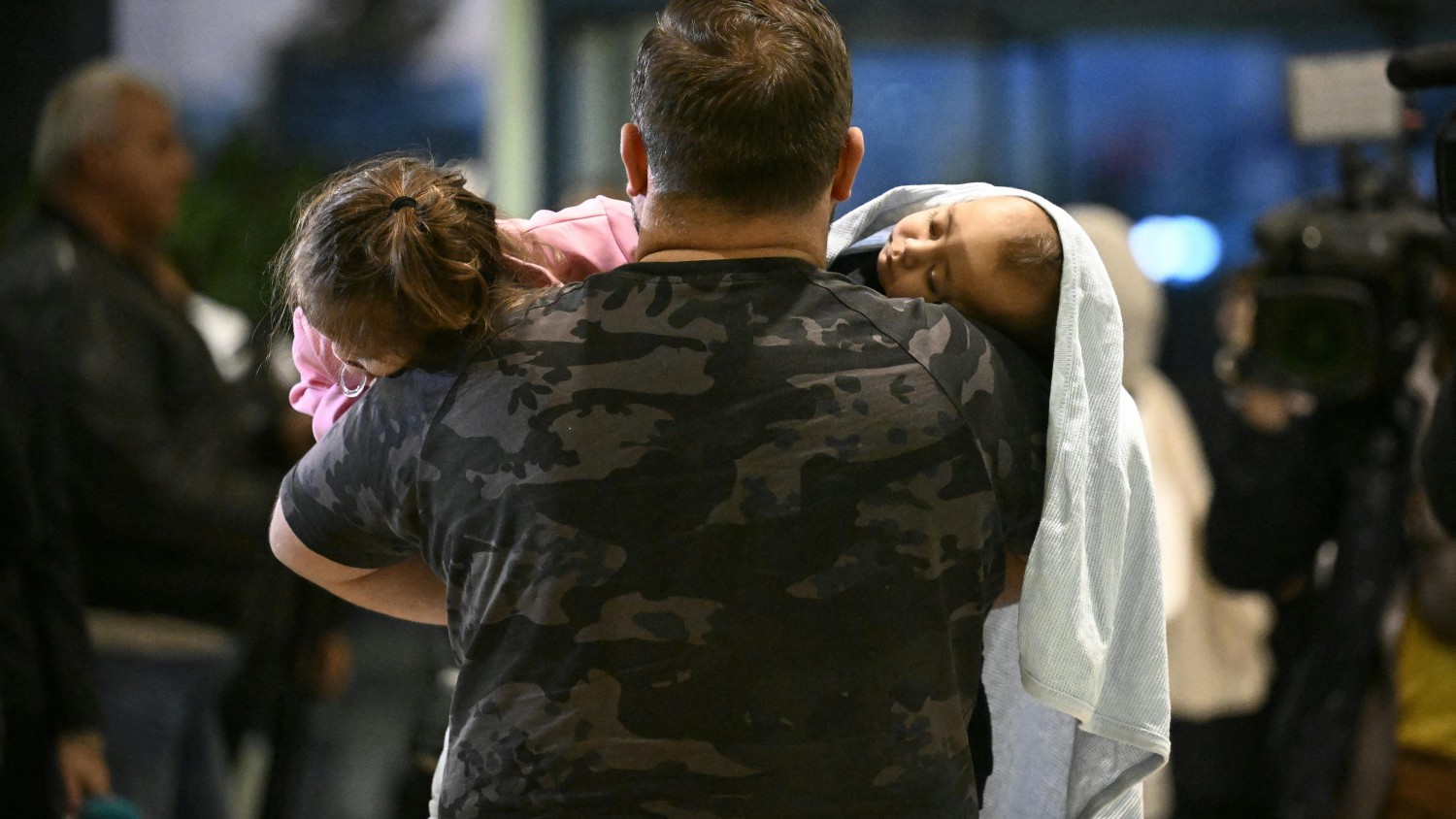 A man carries two children after fleeing Lebanon. Many residents of the country have nowhere to go or cannot afford to leave NIKOLAY DOYCHINOV/AFP