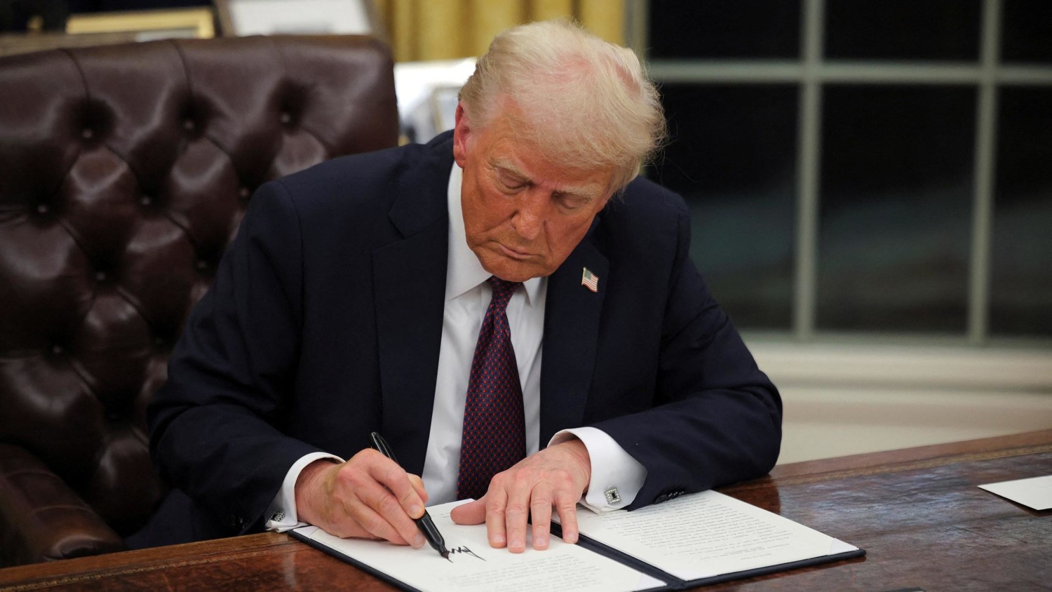 President Donald Trump signs documents as he issues executive orders and pardons for January 6 defendants in the Oval Office at the White House on Inauguration Day in Washington, DC, on January 20. Carlos Barria/Reuters