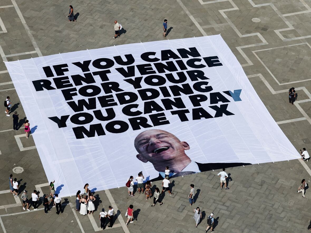 People react to the large anti-Bezos banner that reads: If you can rent Venice for your wedding you can pay more tax. But police quickly took it away. (Yara Nardi/Reuters)
