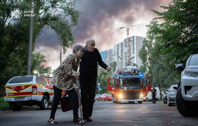 Photo: Services d’urgence ukrainiens via Agence France-Presse  Un couple de personnes âgées traverse une rue près d’un site frappé par la Russie, vendredi, à Kiev.