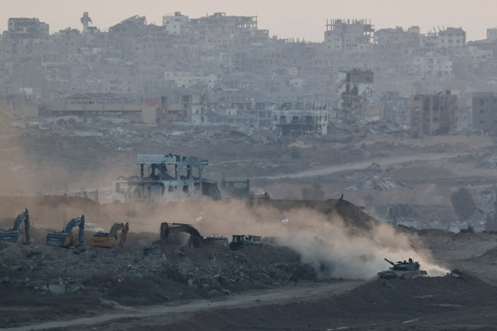 An Israeli tank near heavy machinery, with Gaza visible in the background. Photo: amir cohen/Reuters