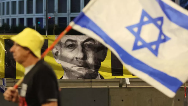 Un manifestant brandit le drapeau israélien lors d'une manifestation antigouvernementale devant le ministère israélien de la Défense dans la ville côtière de Tel Aviv, le 29 mars 2025. © Jack Guez, AFP
