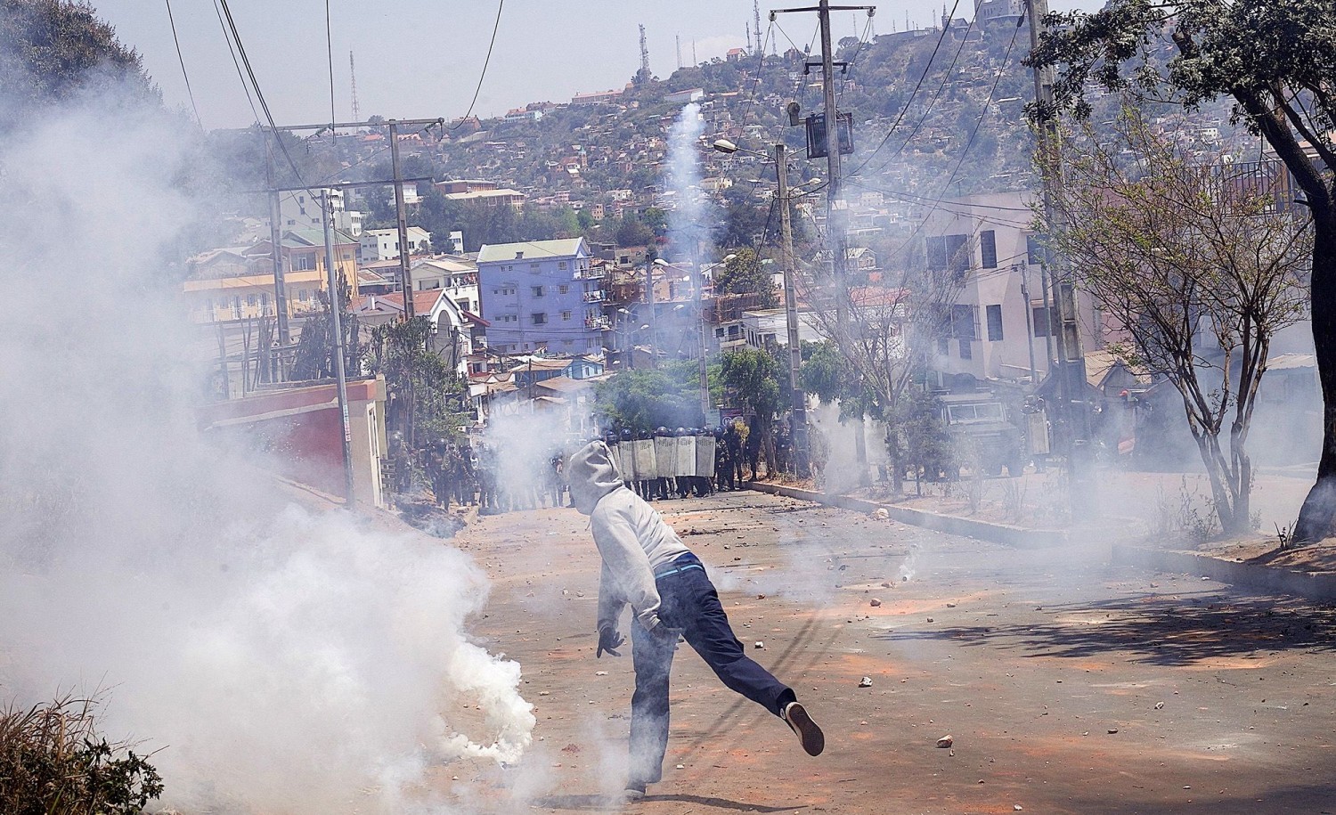 A protester throws back a tear gas canister lobbed by riot police during a demonstration denouncing frequent power outages and water shortages, near the University of Antananarivo, Madagascar, on Monday. Zo Andrianjafy/Reuters