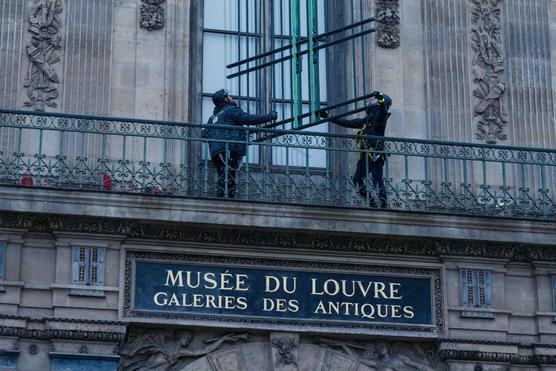 Workers install iron window guards on the window of the Galerie d'Apollon of the Louvre Museum, on the Quai Francois Mitterrand side, in Paris on December 23, 2025. DIMITAR DILKOFF / AFP