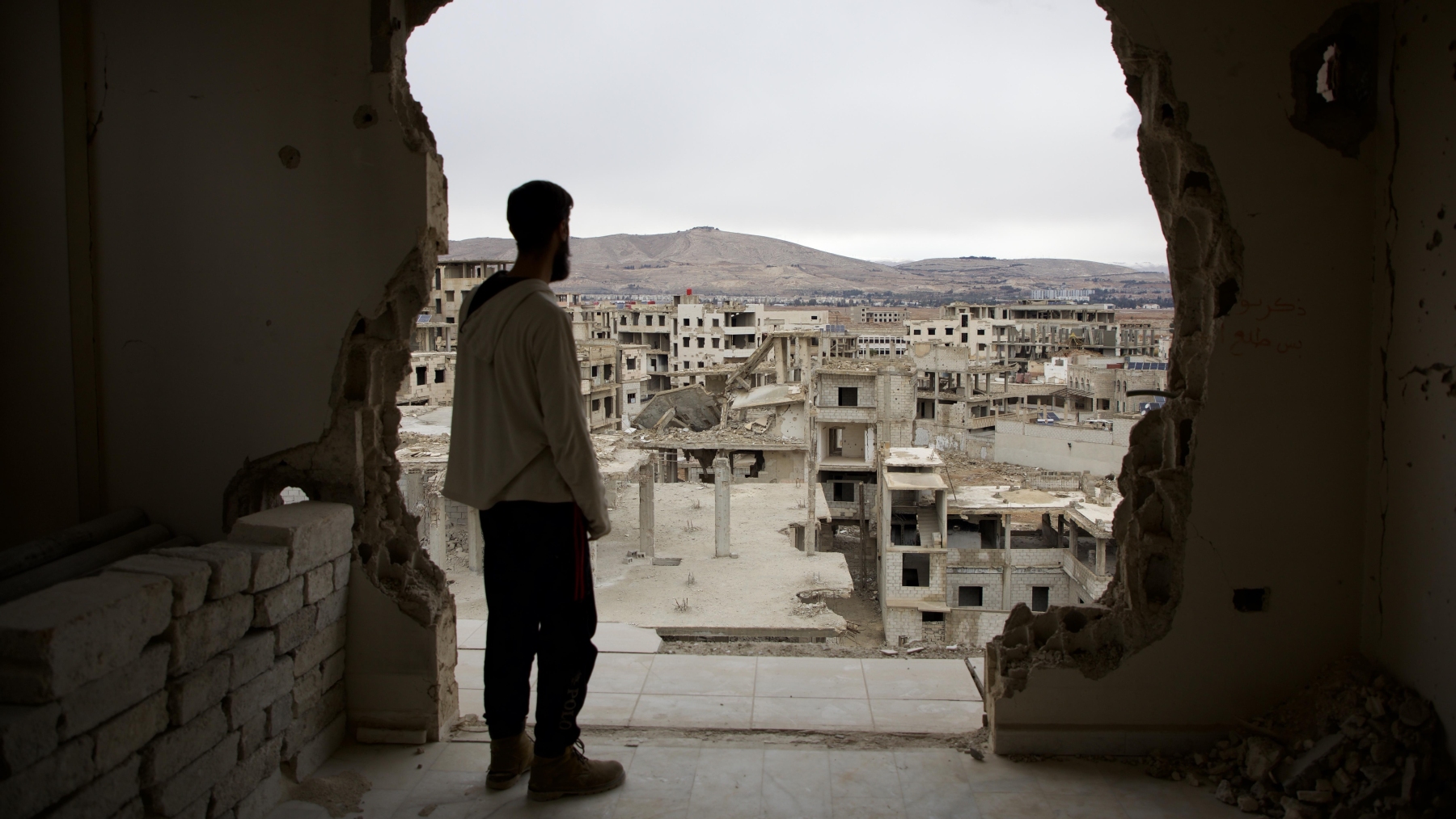 Un homme regarde des bâtiments endommagés durant les 14 ans de guerre civile en Syrie. Photo prise à Darayya, près de Damas, le 30 décembre 2024. PHOTO : GETTY IMAGES / ALI HAJ SULEIMAN