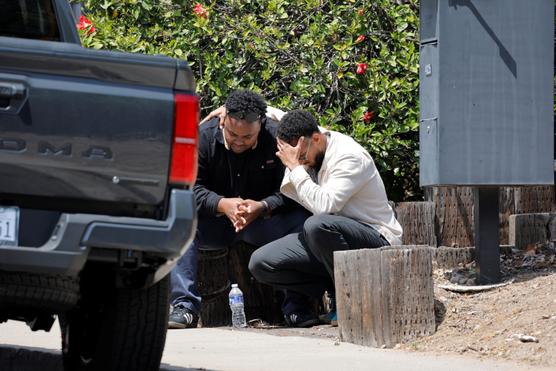 Deux hommes se réconfortent près des lieux où deux hommes ont ouvert tuant trois personnes à la mosquée de San Diego (Californie), le 18 mai 2026. MIKE BLAKE/REUTERS