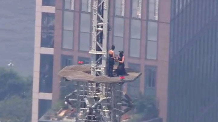 Two people climb to the top of Empire State Building with massive banner