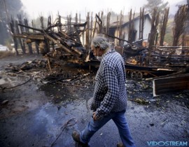 Homeowner Alan Barnard walks past the remains of his RV from a wildfire in the Lake View Terrace area of Los Angeles on Dec. 5, 2017.