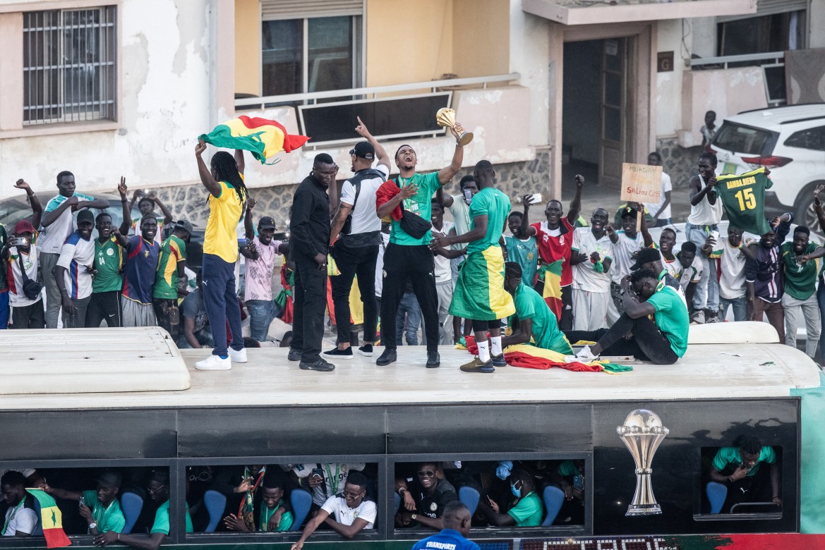 Supporters cheer as Abdou Diallo raises the trophy in Dakar. [John Wessels/AFP]