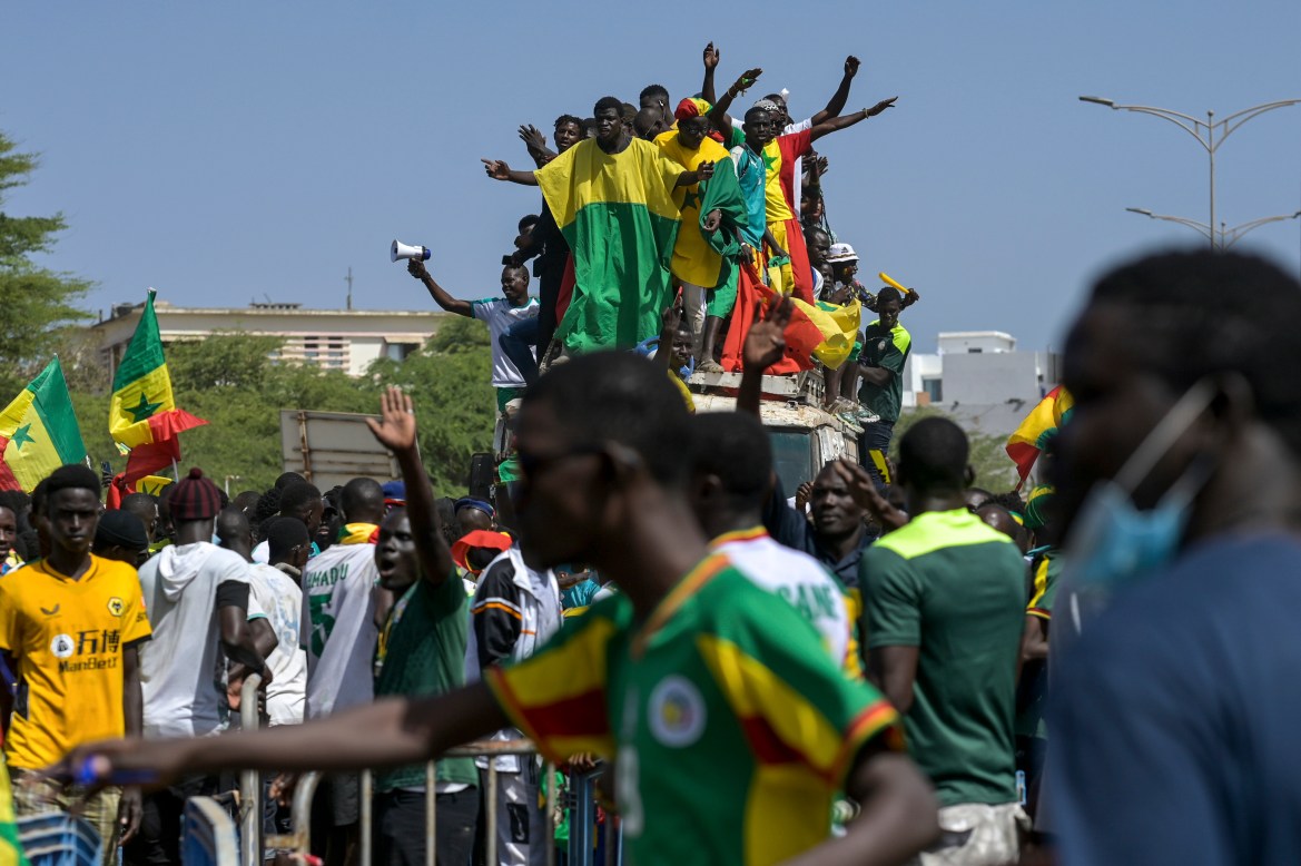 Senegalese football fans celebrate as they await the return of their national team in Dakar. [Sylvain Cherkaoui/AP Photo]